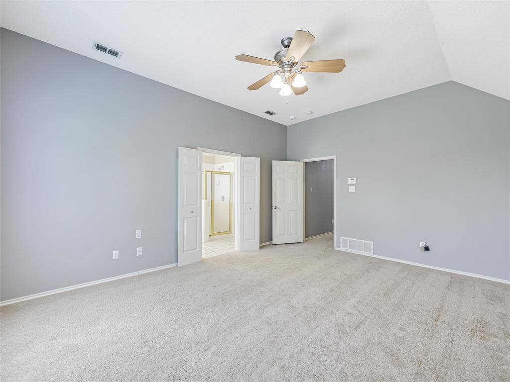 Room featuring vaulted ceilings, carpeted flooring, neutral wall paint, and a ceiling fan with integrated lighting