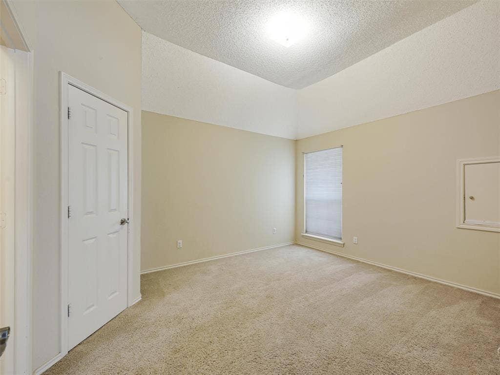 Vaulted ceilings, neutral wall color, wall-to-wall carpeting, single-panel interior door, and window with built-in blinds
