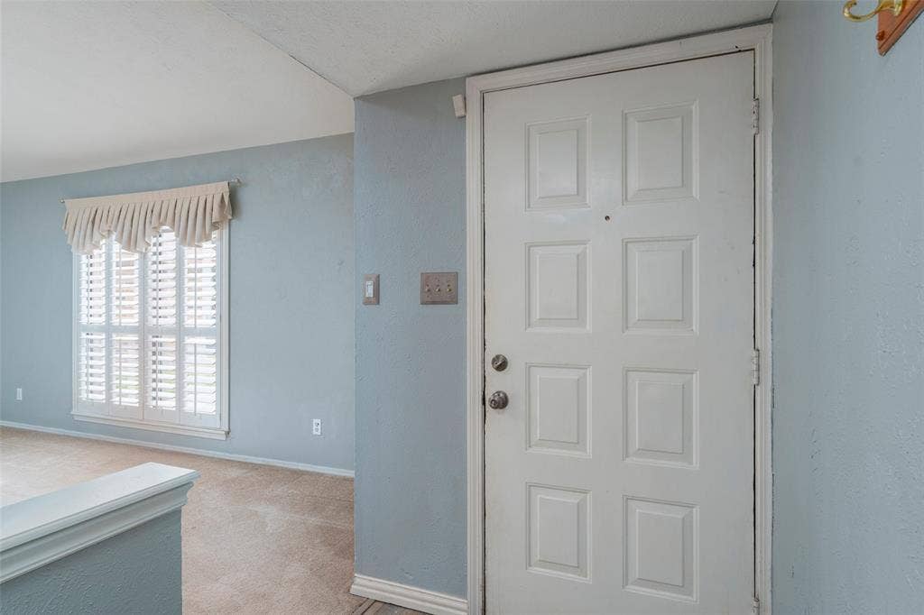 826 Camino Court, Grand Prairie, TX 75052 Entryway featuring a white paneled door, plantation-style window shutters, and textured wall finish
