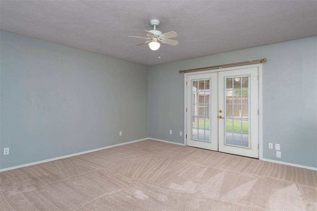 826 Camino Court, Grand Prairie, TX 75052 Neutral-toned interior space featuring light-colored wall-to-wall carpeting, a white ceiling fan with integrated lighting, and white French doors with glass panes