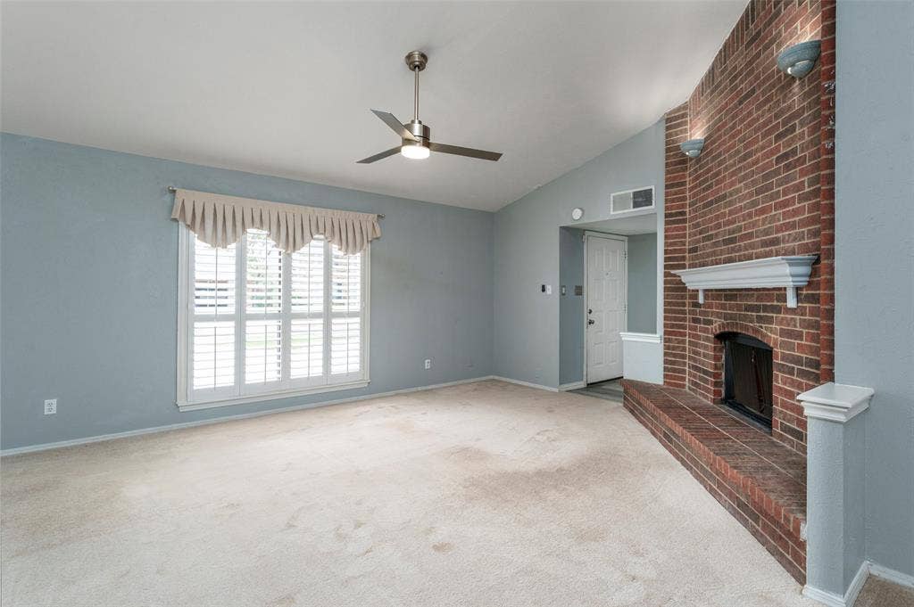 826 Camino Court, Grand Prairie, TX 75052 Vaulted ceiling featuring a ceiling fan, full-height red brick fireplace with a built-in mantle, and window shutters