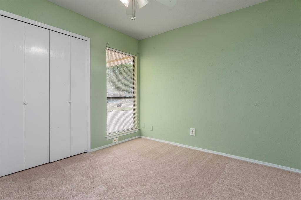 826 Camino Court, Grand Prairie, TX 75052 Interior room featuring neutral carpeting, floor-to-ceiling bi-fold closet doors, a vertical window, and an overhead ceiling fan