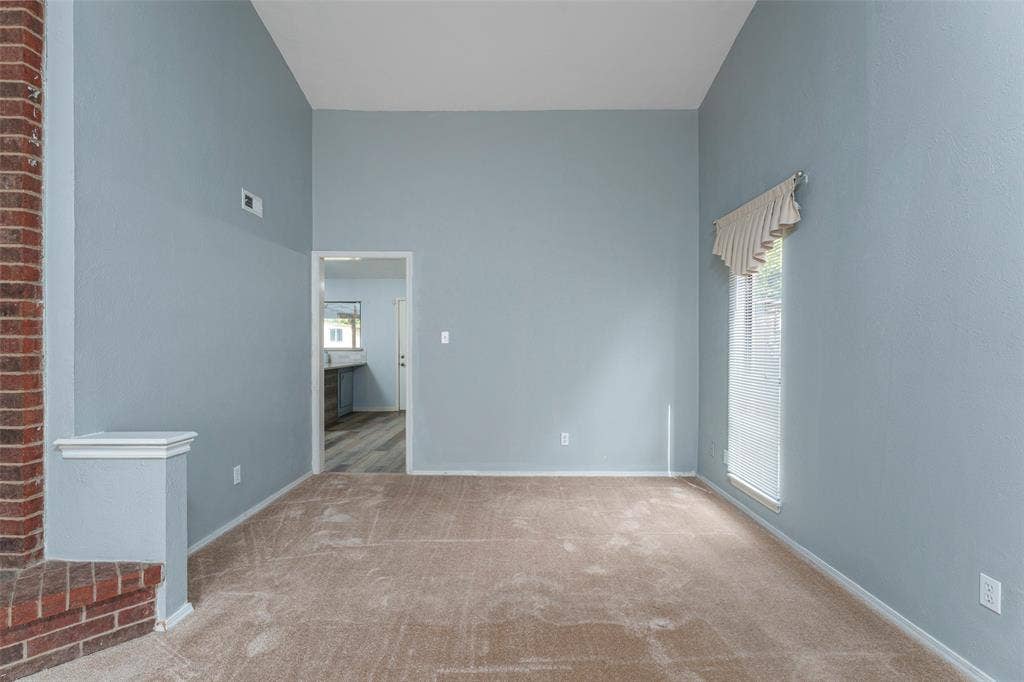 826 Camino Court, Grand Prairie, TX 75052 High-ceilinged room featuring a floor-to-ceiling brick fireplace, carpeted flooring, and a vertical window