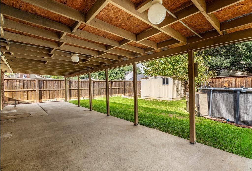 826 Camino Court, Grand Prairie, TX 75052 Covered patio with exposed beam ceiling, concrete flooring, privacy wood fencing, and an exterior storage structure