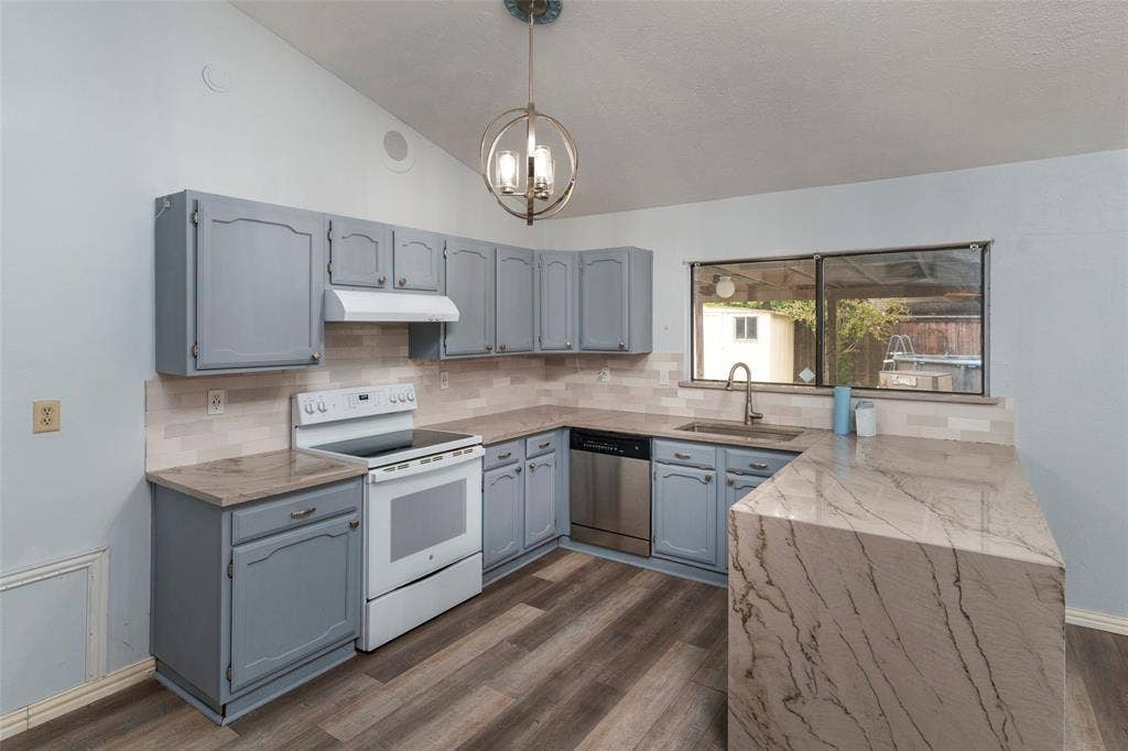 826 Camino Court, Grand Prairie, TX 75052 Kitchen featuring blue cabinetry, stone-finish countertops, a waterfall-edge breakfast bar, wood-finish flooring, and a metal orb pendant light fixture