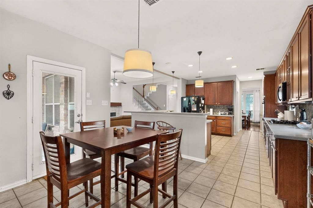 Kitchen featuring stained wood cabinetry, stone-finish countertops, ceramic tile flooring, recessed lighting, and pendant fixtures