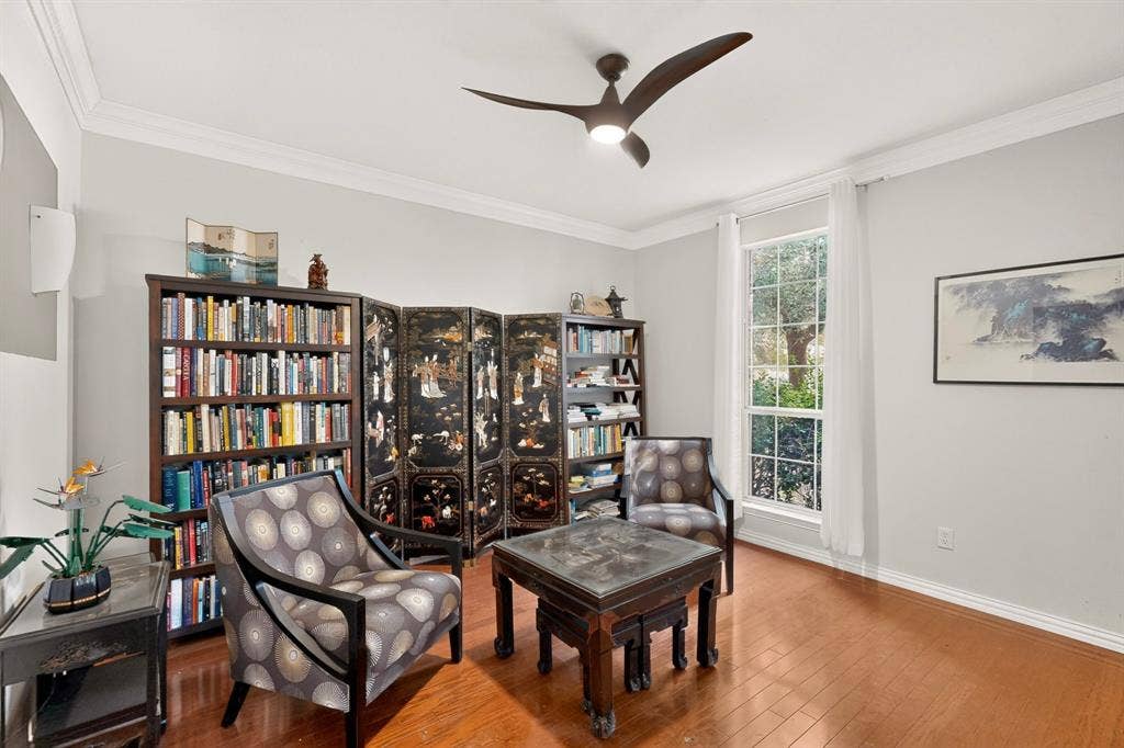 Formal living room featuring wood-flooring, crown molding, and a modern three-blade ceiling fan with integrated lighting