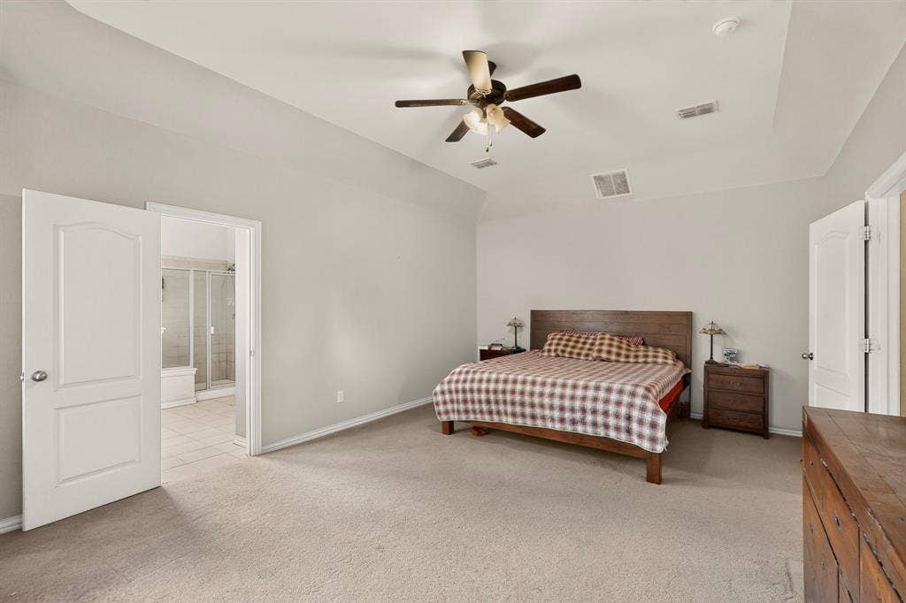 Spacious room featuring a tray ceiling, neutral wall tones, wall-to-wall carpeting, and a ceiling fan with integrated lighting
