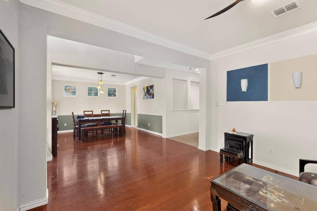 Wood-finish flooring, crown molding, two-tone wall treatments, and multi-light pendant fixture
