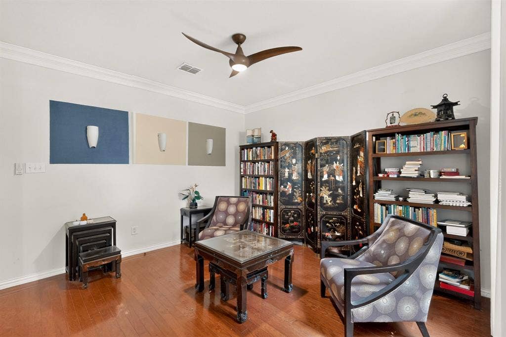 Interior space featuring crown molding, wood-finish flooring, and a multi-blade ceiling fan with integrated lighting
