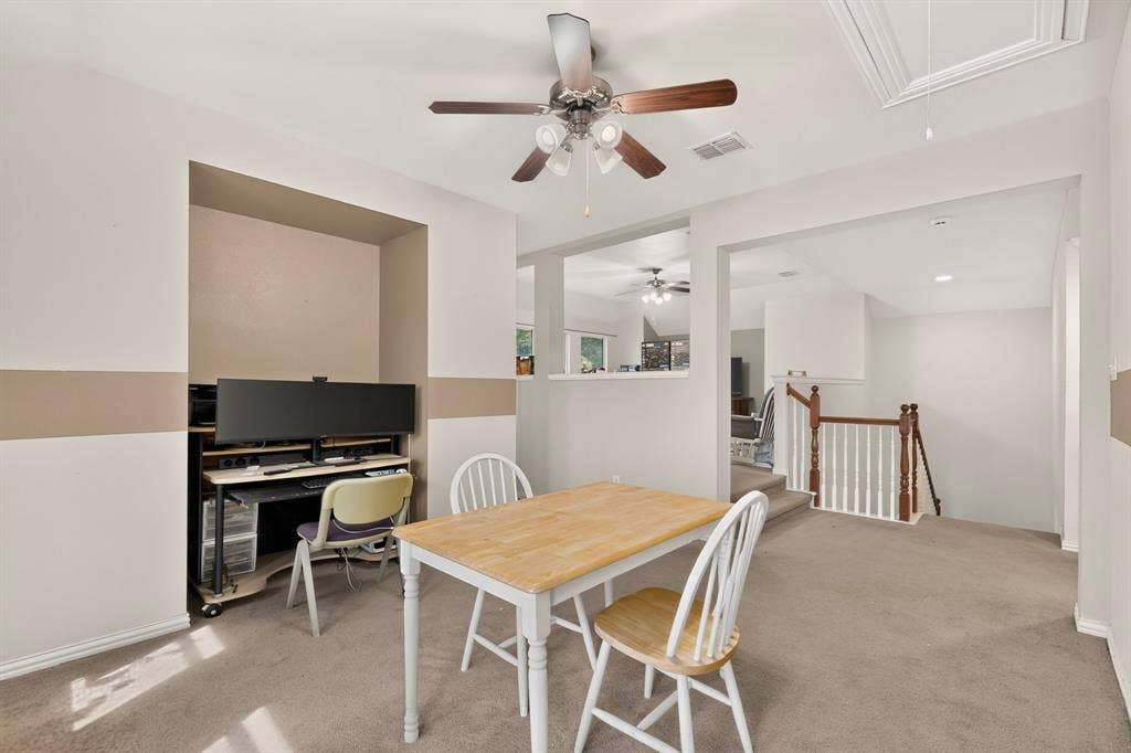 Interior space featuring neutral wall paint with horizontal accent detailing, carpeted flooring, a recessed nook, and a ceiling fan with integrated lighting
