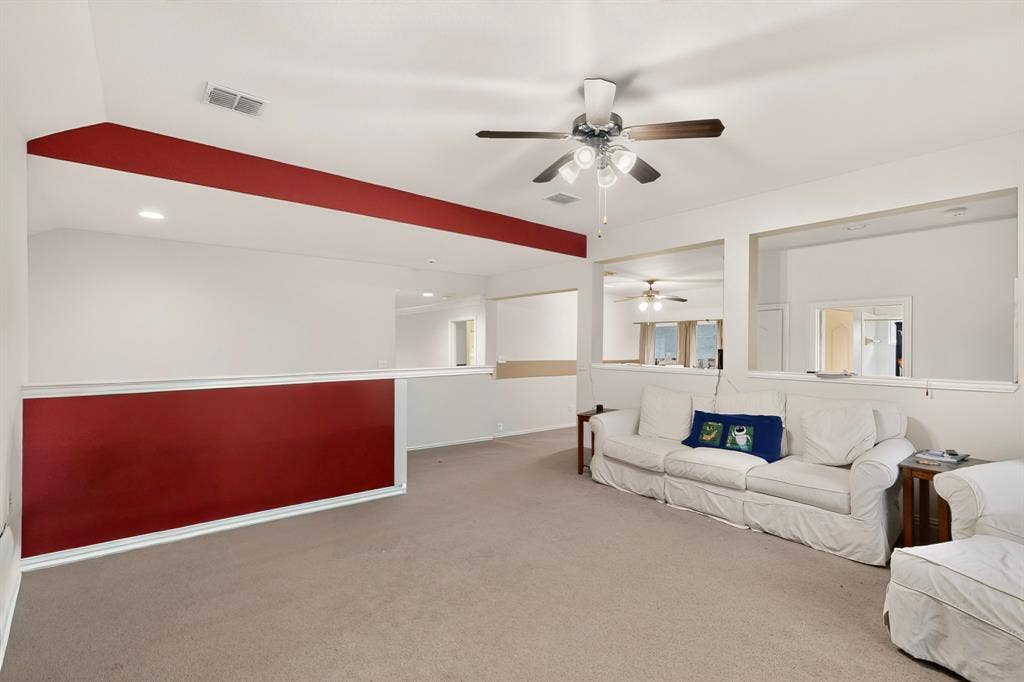 Vaulted ceilings featuring a multi-light ceiling fan, wall cutouts, and neutral carpeting