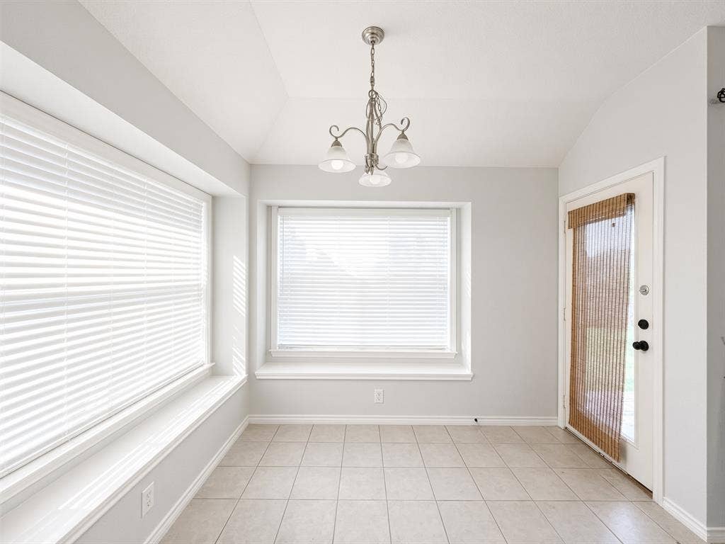 Interior space featuring tile flooring, dual bay windows with integrated sills, a multi-light brushed nickel chandelier, and a glass-paneled exterior door