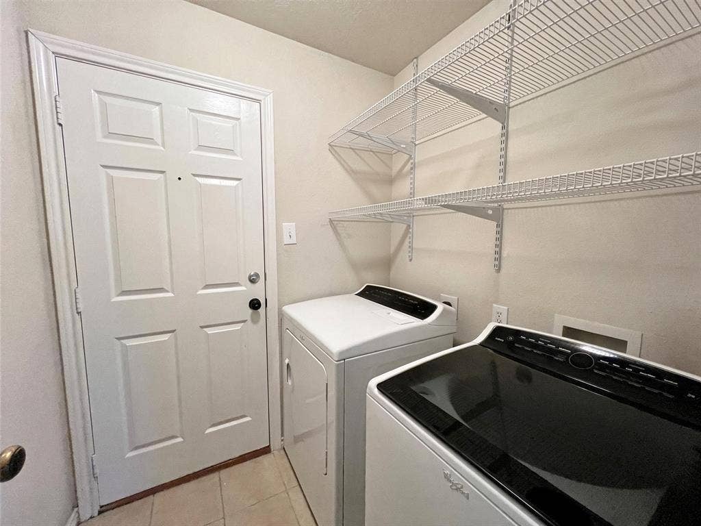 Utility space featuring white tile flooring, a six-panel door, and white wire wall-mounted shelving