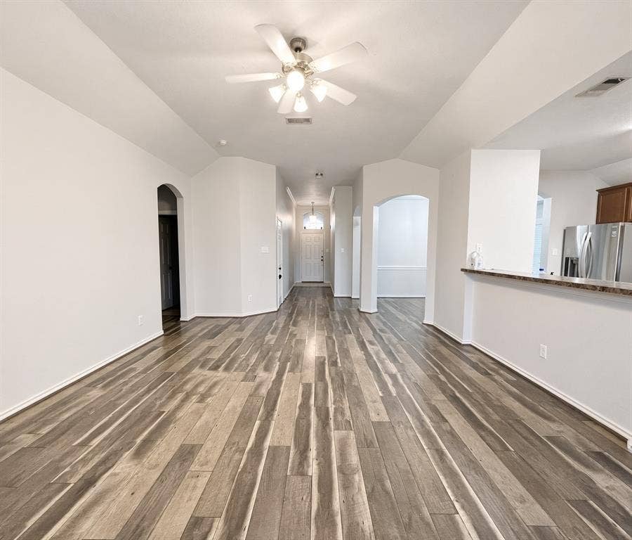 Vaulted ceilings, wood-finish flooring, recessed lighting, ceiling fan with light kit, and arched architectural entryways