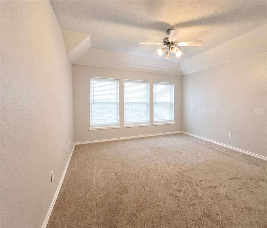 Tray ceiling featuring a central multi-light ceiling fan, neutral wall tones, carpeted flooring, and a trio of windows