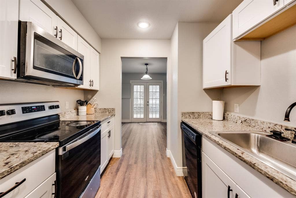 Kitchen featuring white shaker cabinetry, granite countertops, stainless steel appliances, stainless steel sink with a matte black faucet