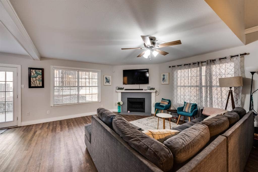 Open living room with a celling fan , tons of natural lighting and a cozy fireplace.