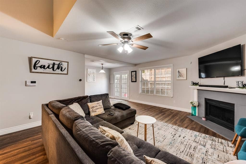 Open living room with a celling fan , natural lighting , and fireplace.
