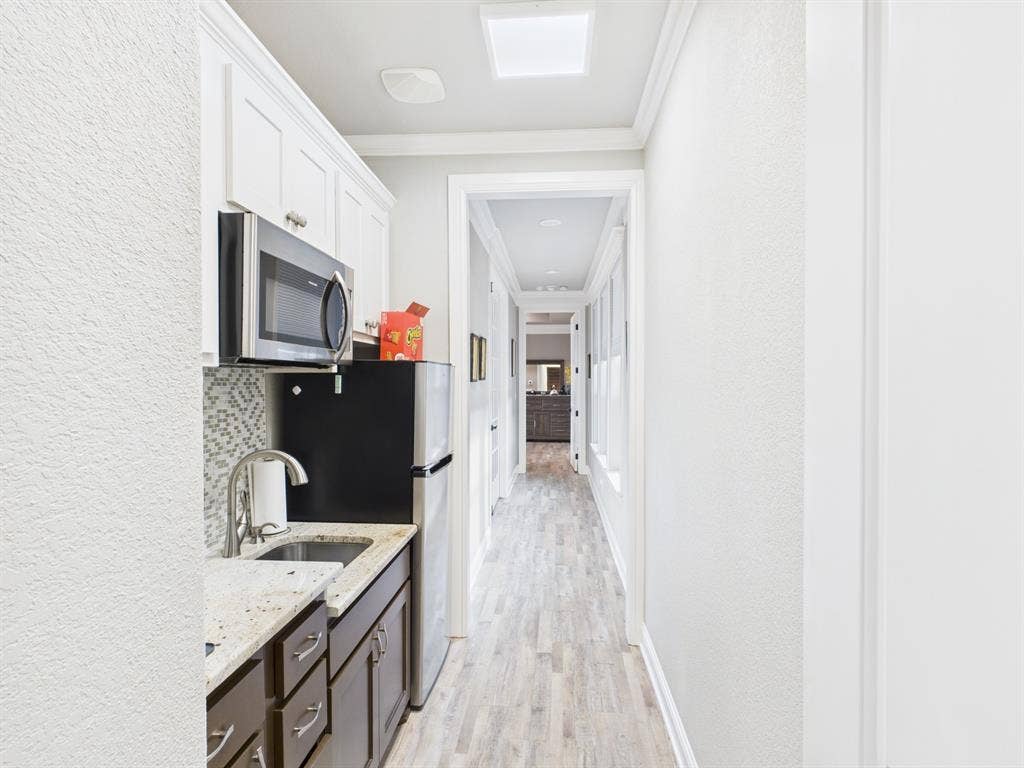 1201 E Iberian Court, Granbury, TX 76048 Kitchenette featuring stone-finish countertops, mosaic tile backsplash, stainless steel microwave, and wood-finish flooring