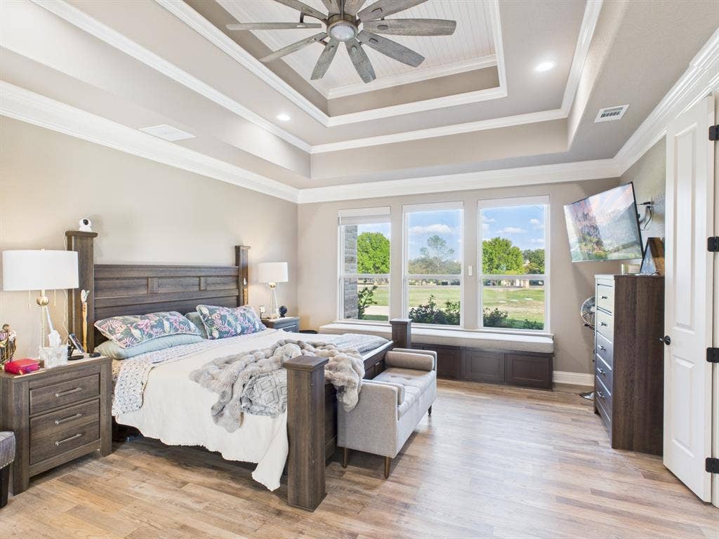 1201 E Iberian Court, Granbury, TX 76048 Tray ceiling with crown molding, wood-finish flooring, ceiling fan with light fixture, built-in window seat, and large windows