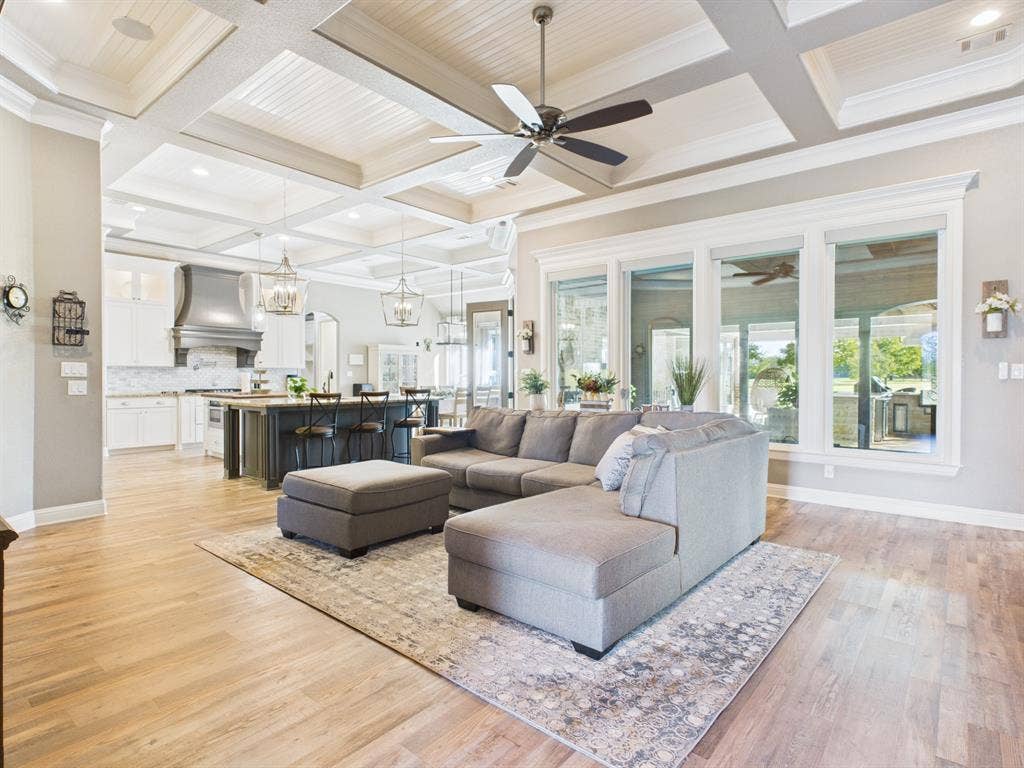 1201 E Iberian Court, Granbury, TX 76048 Coffered ceiling featuring recessed lighting, extensive windows, kitchen with central island and metal range hood, and wood-finish flooring
