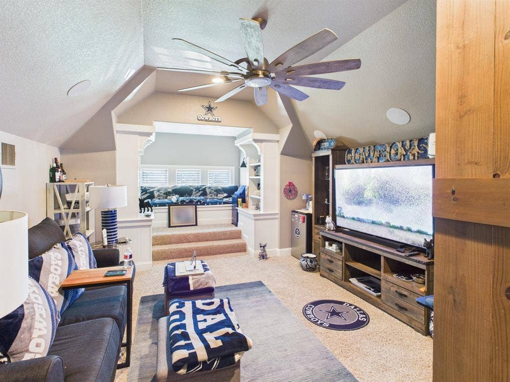 1201 E Iberian Court, Granbury, TX 76048 Vaulted ceiling featuring a multi-blade ceiling fan, built-in shelving, custom window nook with stepped platform, and recessed audio speakers