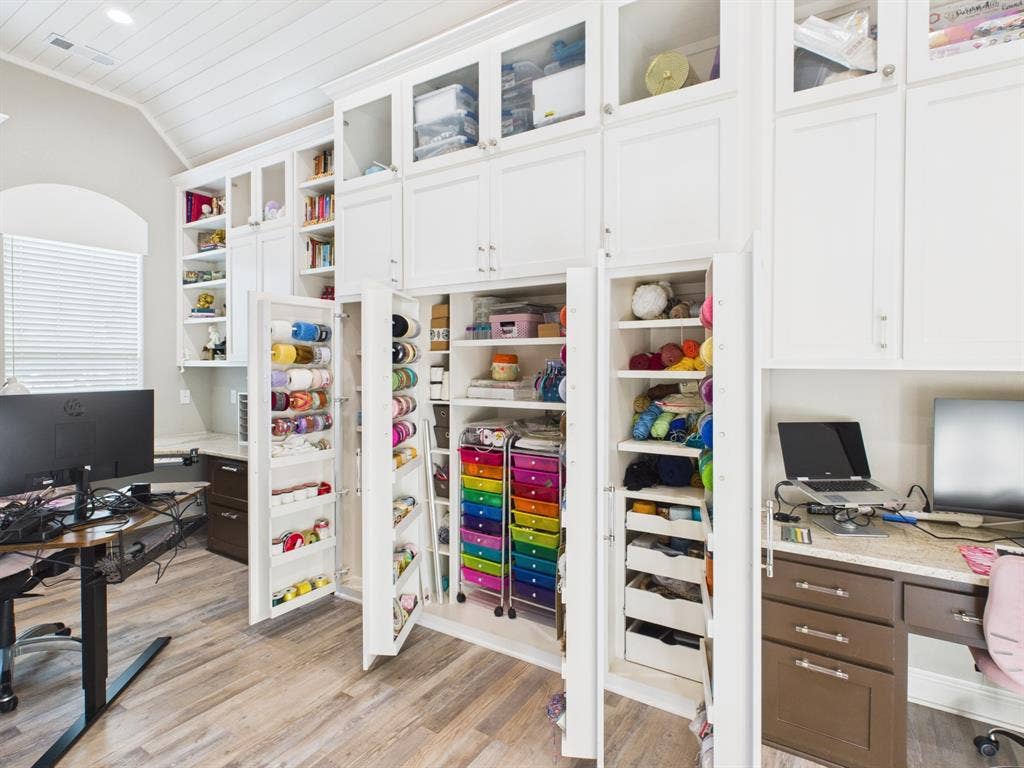 1201 E Iberian Court, Granbury, TX 76048 Custom floor-to-ceiling cabinetry featuring shaker-style doors, glass-front upper displays, pull-out shelving, and integrated workstations with stone countertops, complemented by wood-finish flooring and a vaulted shiplap ceiling