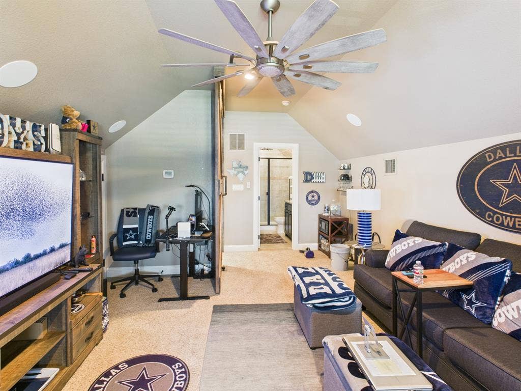 1201 E Iberian Court, Granbury, TX 76048 Vaulted ceiling featuring a large multi-blade industrial-style ceiling fan, neutral wall-to-wall carpeting, and a sliding barn-style door