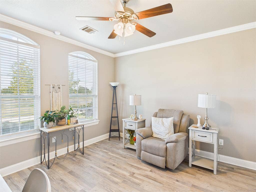 1201 E Iberian Court, Granbury, TX 76048 Room featuring arched windows, wood-finish flooring, crown molding, and a ceiling fan with integrated lighting