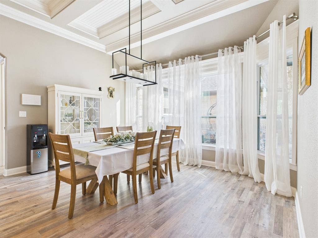 1201 E Iberian Court, Granbury, TX 76048 Tray ceiling with recessed detailing, wood-finish flooring, built-in glass-front cabinetry, and a geometric chandelier