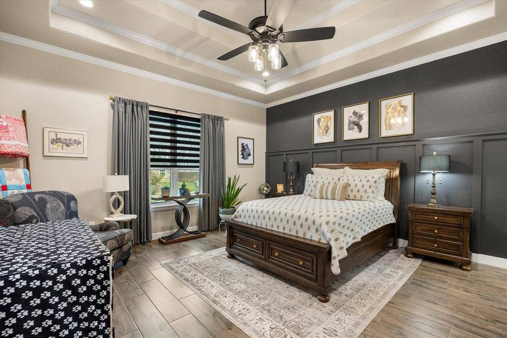 Tray ceiling with crown molding, wood-finish flooring, and decorative wall paneling