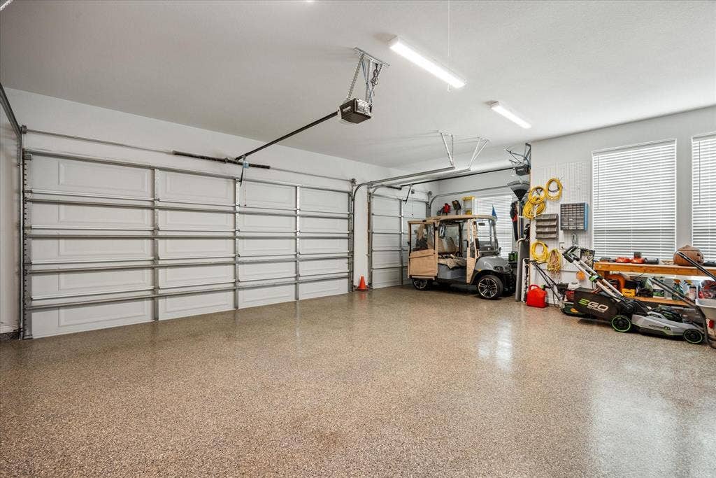 Finished garage featuring an epoxy-coated floor, dual roll-up doors, high-output LED lighting, and windows with integrated blinds