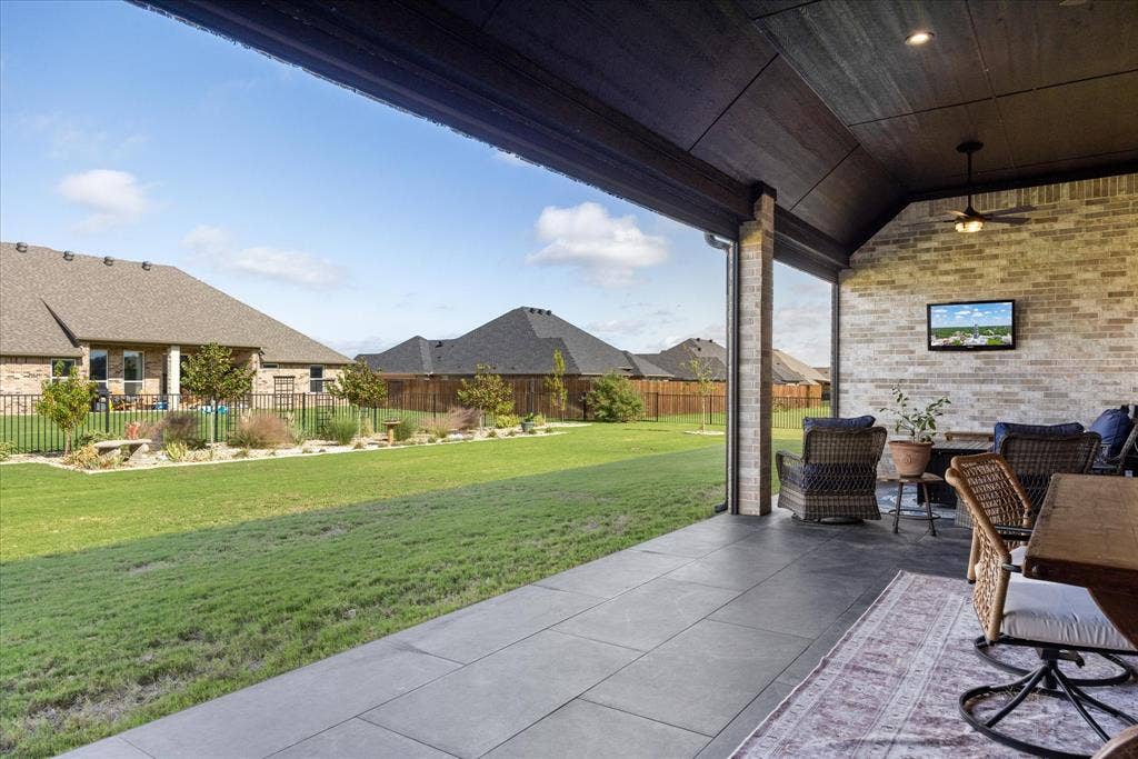 Covered patio featuring large-format tile flooring, a brick accent wall, recessed lighting, and a ceiling fan