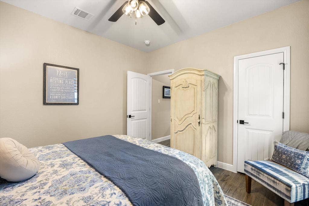 Neutral-toned walls paired with dark wood-finish flooring, white paneled interior doors, matte black hardware, and a ceiling-mounted fan with light fixture