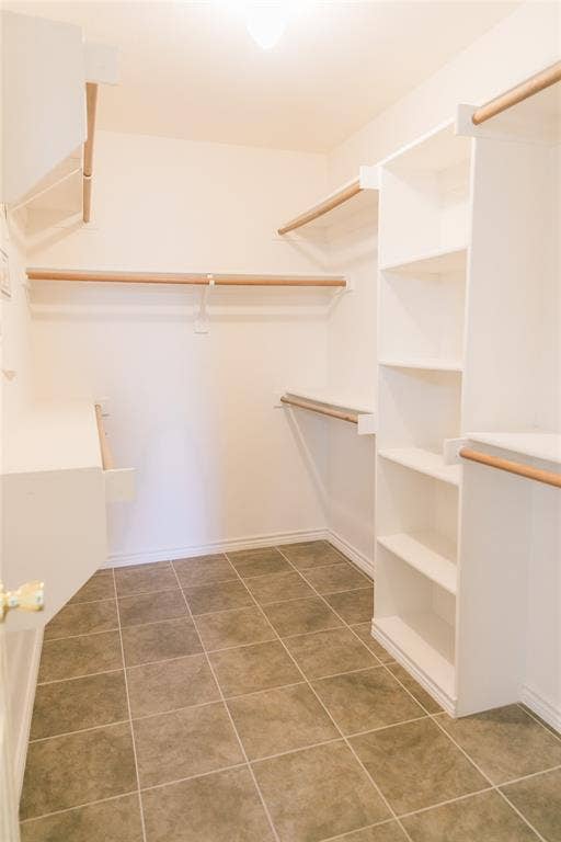 404 Belmont Court, Lewisville, TX 75067 Walk-in closet featuring white built-in shelving, wooden garment rods, and ceramic tile flooring