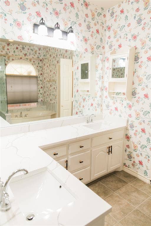 404 Belmont Court, Lewisville, TX 75067 Dual-sink vanity featuring white cabinetry, stone-finish countertops, wall-mounted storage, and a three-light fixture