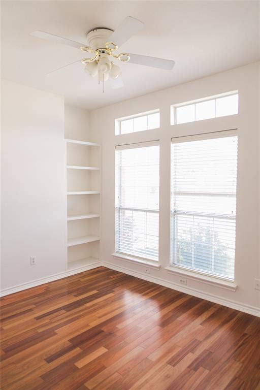 404 Belmont Court, Lewisville, TX 75067 Wood-finish flooring, built-in shelving, dual windows with transom panes, and a ceiling fan with integrated lighting