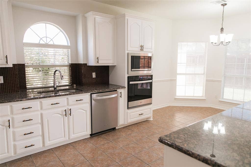 404 Belmont Court, Lewisville, TX 75067 Kitchen featuring white shaker-style cabinetry, stone-surface countertops, a dark mosaic tile backsplash, stainless steel built-in double ovens, and ceramic tile flooring
