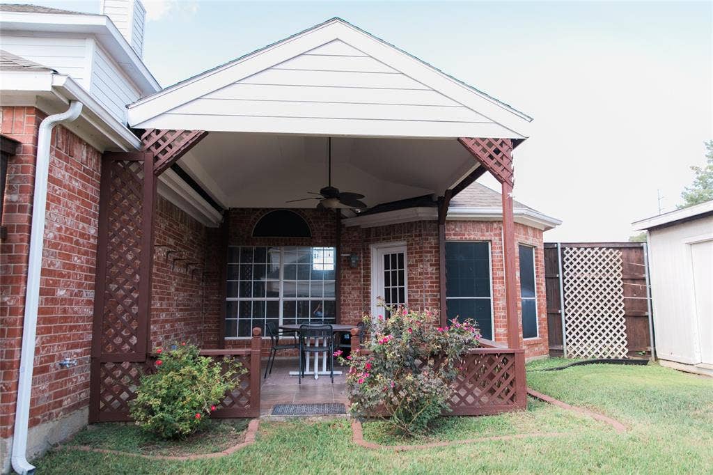 404 Belmont Court, Lewisville, TX 75067 Covered patio featuring a vaulted ceiling with an integrated fan, brick exterior, lattice privacy screening, and tile flooring