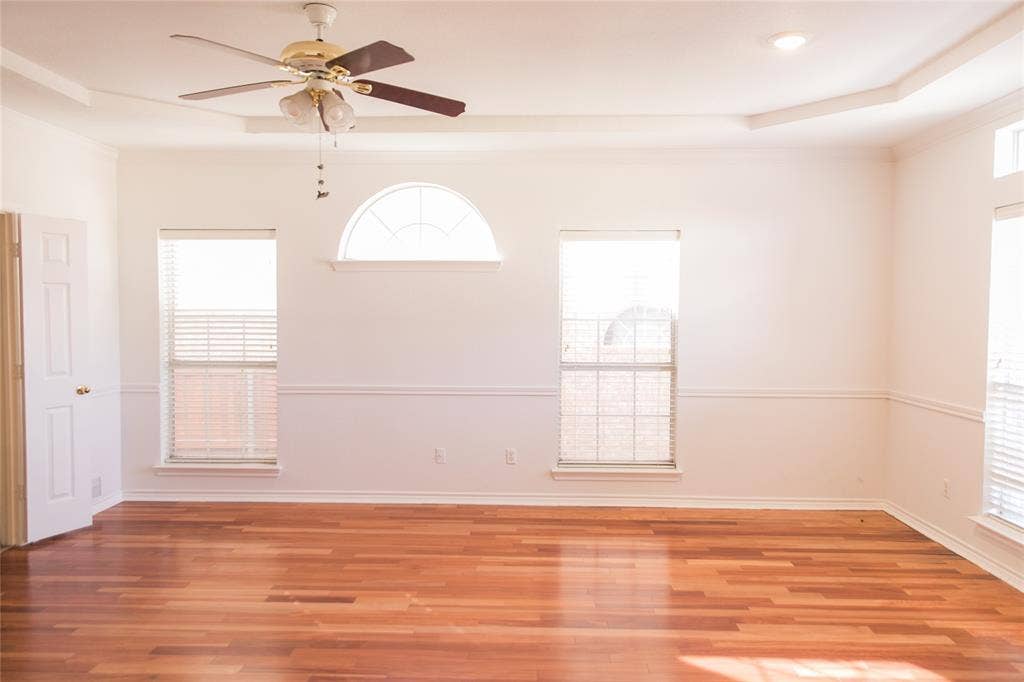 404 Belmont Court, Lewisville, TX 75067 Wood-finish flooring, tray ceiling, ceiling fan with integrated lighting, arched window, and chair rail molding