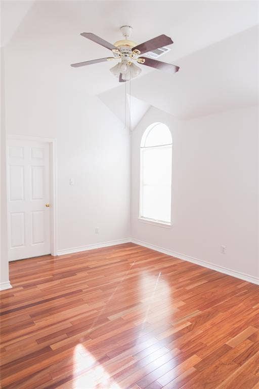 404 Belmont Court, Lewisville, TX 75067 Vaulted ceiling featuring an arched window, wood-finish flooring, and a multi-blade ceiling fan with integrated lighting