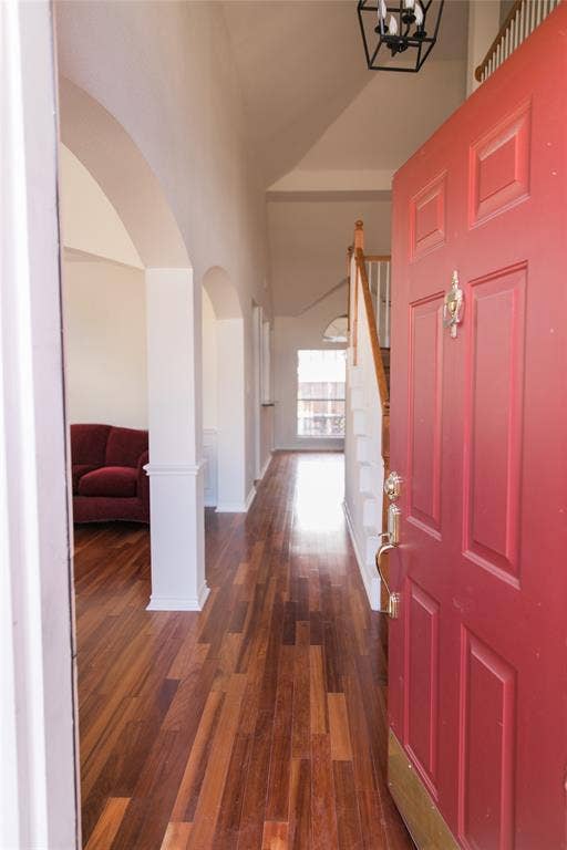 404 Belmont Court, Lewisville, TX 75067 Foyer featuring wood-finish flooring, vaulted ceilings, arched architectural openings, and a staircase with a wooden handrail