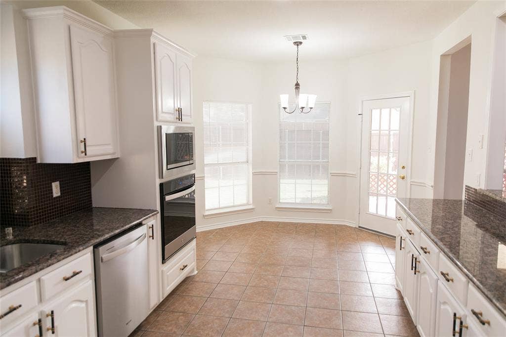 404 Belmont Court, Lewisville, TX 75067 Kitchen featuring white cabinetry, stone countertops, integrated stainless steel double oven, tile flooring, and bay window area