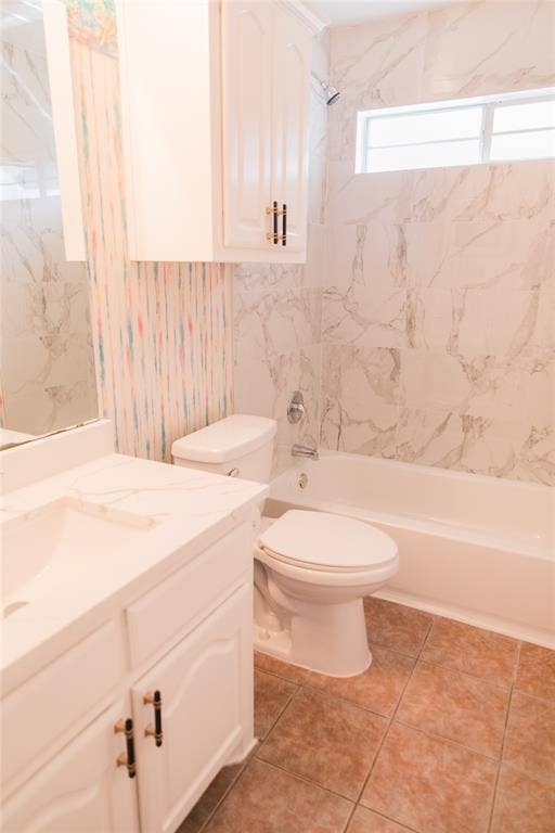 404 Belmont Court, Lewisville, TX 75067 Bathroom featuring a vanity with stone-finish countertop, white cabinetry with contrast hardware, full-height wall tiling, integrated bathtub, and upper transom window