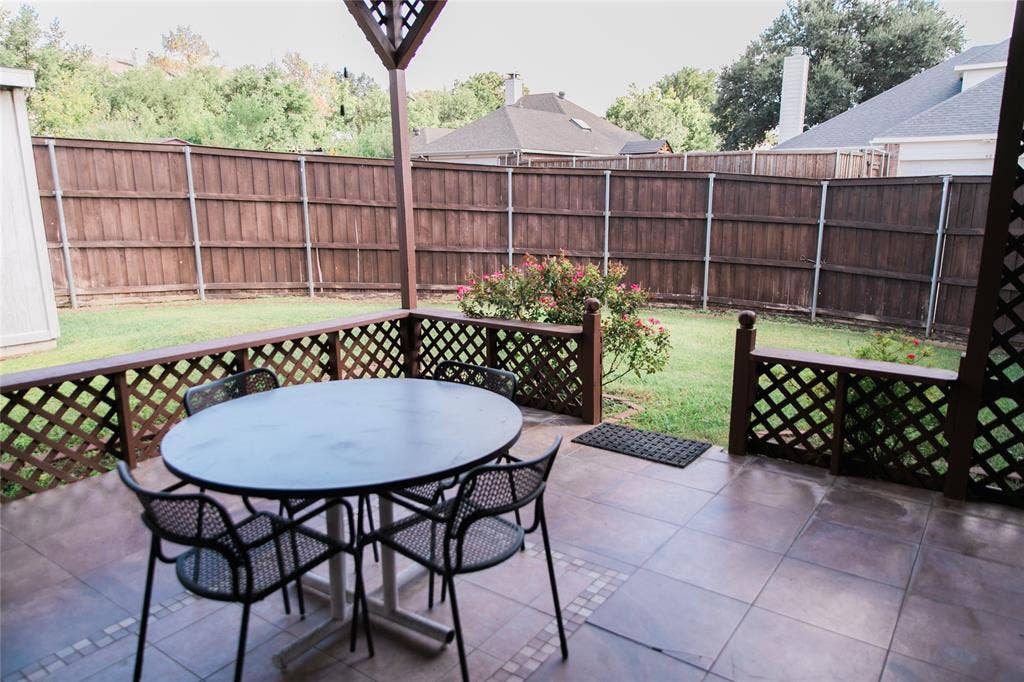 404 Belmont Court, Lewisville, TX 75067 Covered patio with tiled flooring, wood lattice perimeter railing, and a private fenced backyard