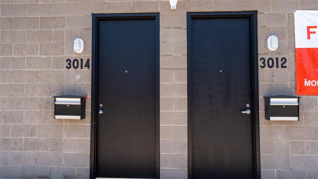 3012 Canton Street, Dallas, TX 75226 Exterior entryway featuring concrete masonry unit siding, matte black flush-mount entry doors, wall-mounted metallic mailboxes, and oval-shaped bulkhead lighting fixtures