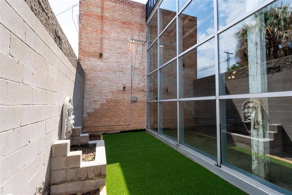 3012 Canton Street, Dallas, TX 75226 Exposed brick masonry walls, floor-to-ceiling glass paneling, concrete block privacy walls, and turf ground cover