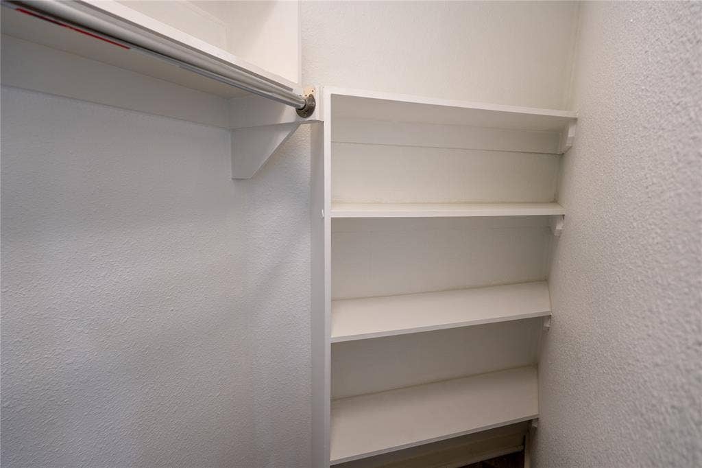 3012 Canton Street, Dallas, TX 75226 Built-in white shelving unit featuring four storage tiers and a wall-mounted metal garment rod with overhead shelf