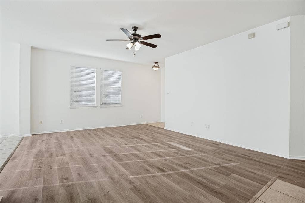 1507 Bankston Drive, Wylie, TX 75098 Interior room featuring wood-finish flooring, white walls, a ceiling fan with integrated lighting, and dual windows with horizontal blinds